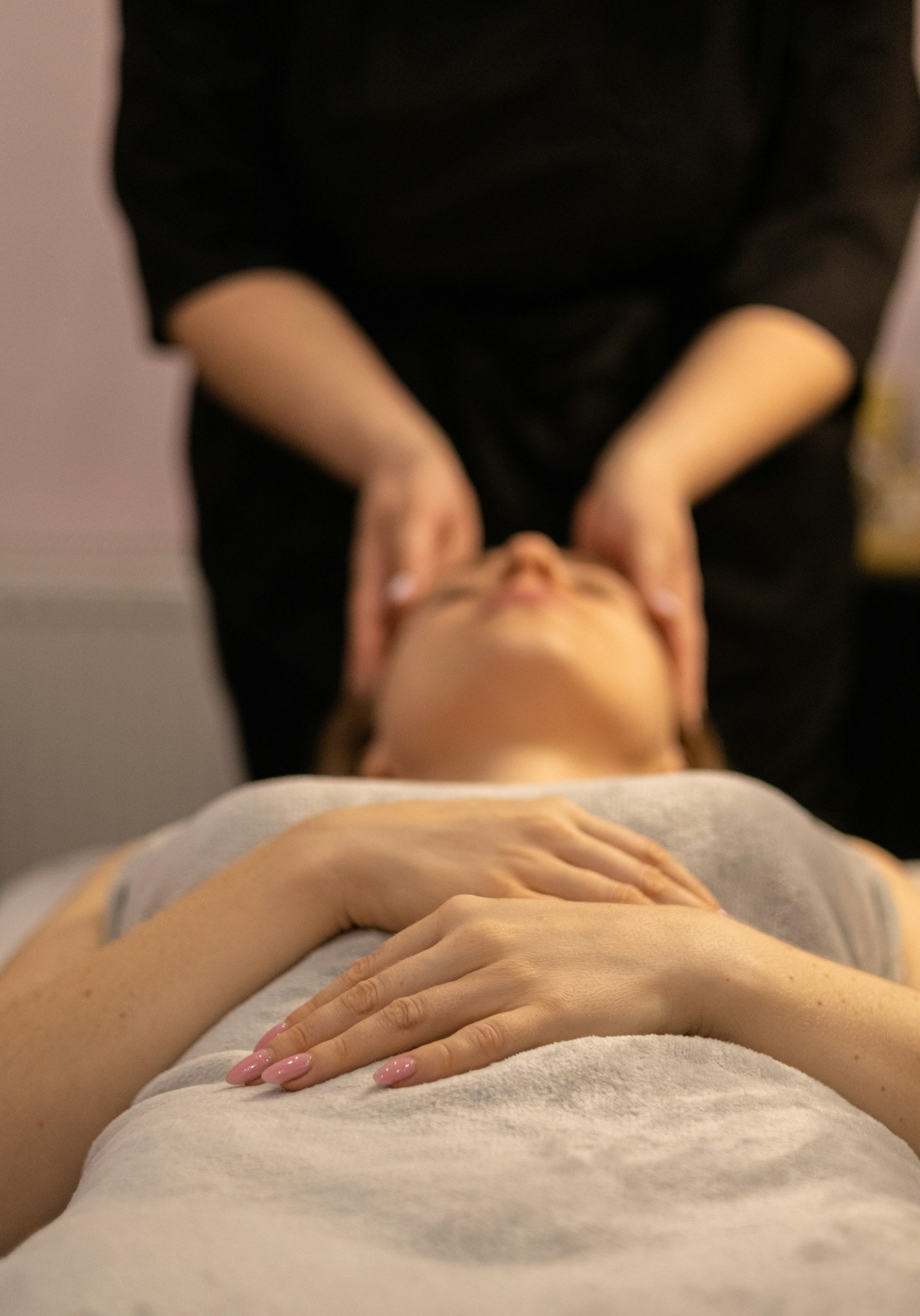 Soin du visage : les mains de la praticienne sur les tempes d’une cliente détendue