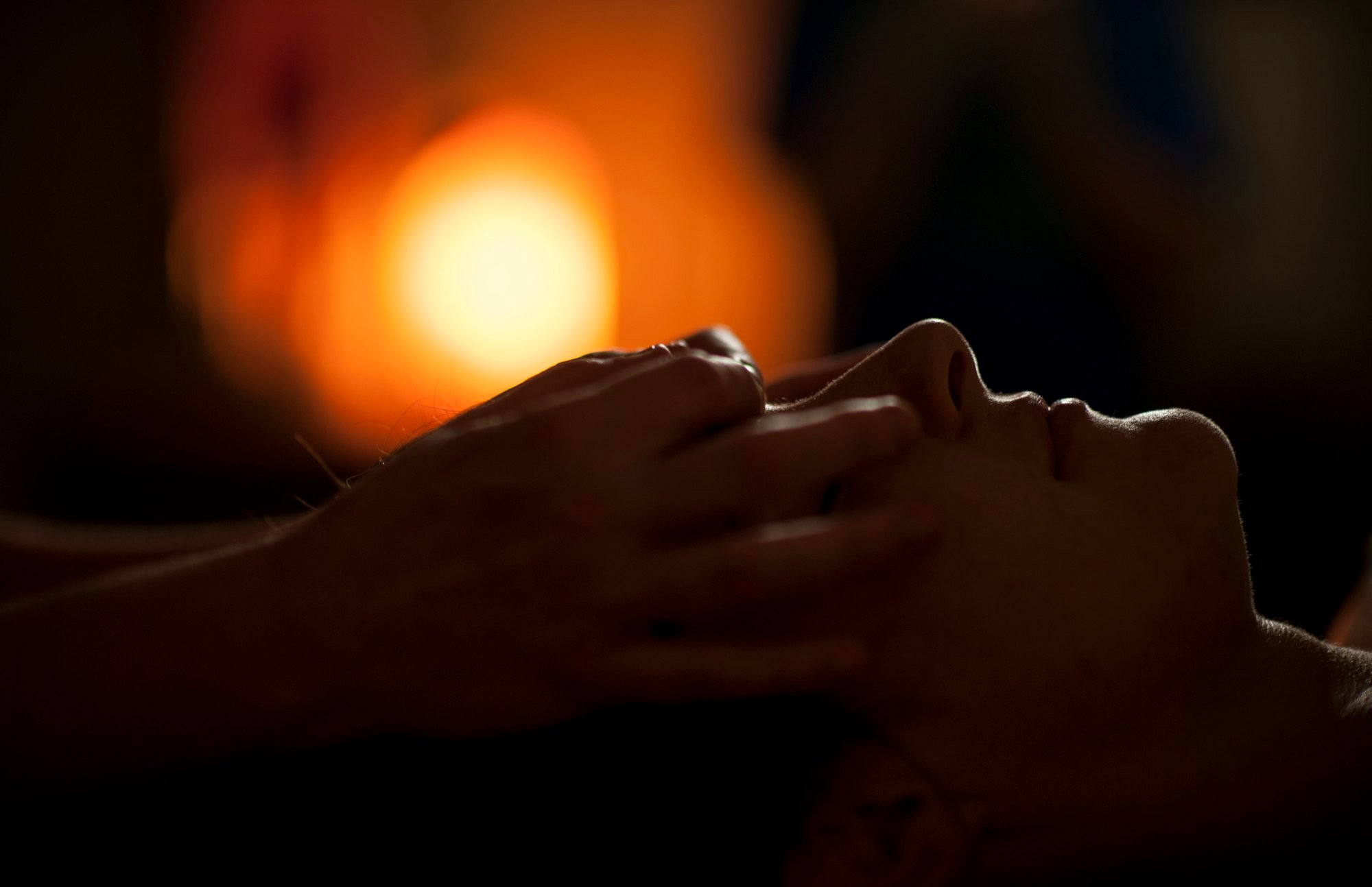 Massage du visage à la lueur d’une lampe, les yeux fermés